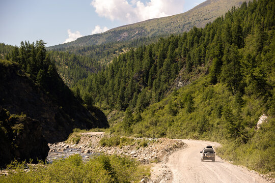 Japanese SUV moving by a road near a mountain river