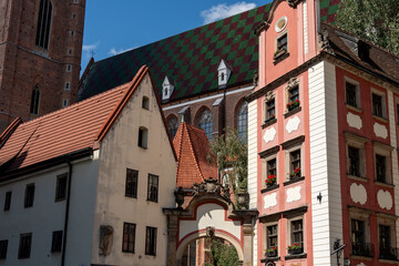 Old town buildings with colorful facades in Wroclaw with church tower and patterned roof in background. High quality photo