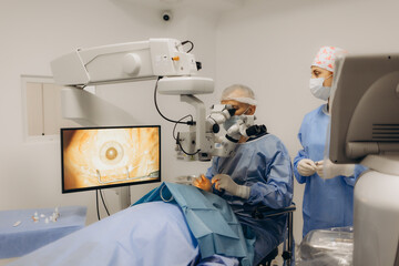 Skilled surgeon and his medical team performs precise eye surgery on an elderly patient, restoring...