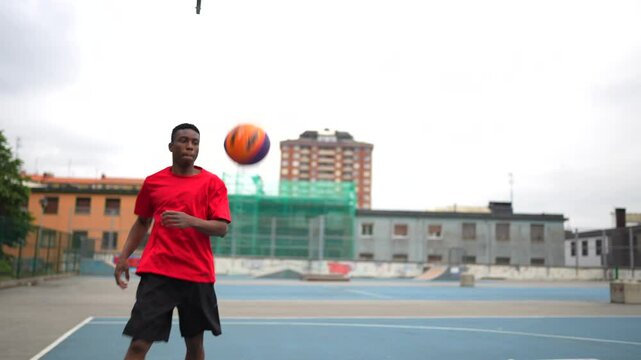 Video of a basketball player throwing a ball in an outdoor blue basketball court