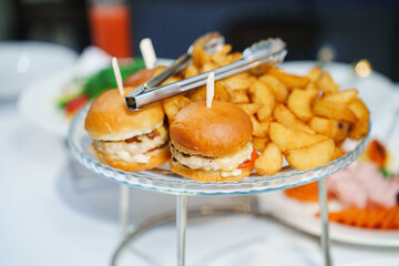  a tray of fried potatoes and burgers on the table. catering for a festive banquet.