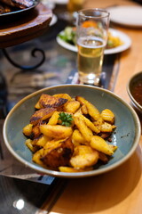 Roasted potatoes in a dish next to a glass of bear. Top, close up shot, shallow depth of field, no people