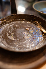 Cast iron saucer pan or skillet stained with leftover sauce. Top view, close up shot, shallow depth of field, no people