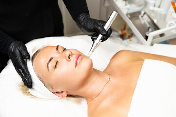 Microneedle RF lifting procedure. A cosmetologist performs a facial rejuvenation procedure on a...