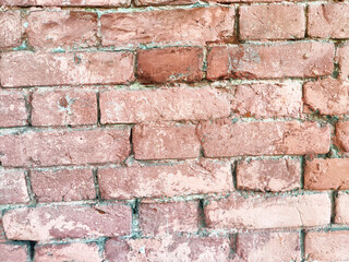 The surface of a weathered red brick wall displays unique textures, color shades, and irregularities with visible mortar lines