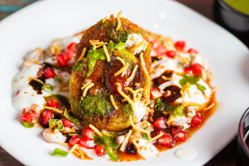 Dabeli is a spicy Indian street food made with a potato filling, tamarind chutney, and sev, served in a bun.