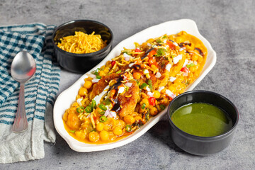 Dabeli is a spicy Indian street food made with a potato filling, tamarind chutney, and sev, served in a bun.