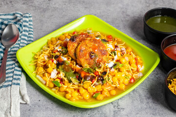 Dabeli is a spicy Indian street food made with a potato filling, tamarind chutney, and sev, served in a bun.