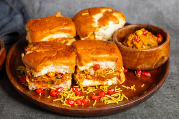 Dabeli is a spicy Indian street food made with a potato filling, tamarind chutney, and sev, served in a bun.