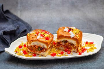 Dabeli is a spicy Indian street food made with a potato filling, tamarind chutney, and sev, served in a bun.