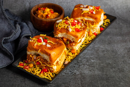 Dabeli is a spicy Indian street food made with a potato filling, tamarind chutney, and sev, served in a bun.