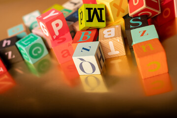 A colorful jumble of alphabet blocks on a gold background The letters are scattered in a random...