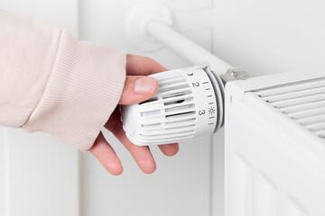 A woman turns up the temperature on a heating radiator as the cold weather sets in