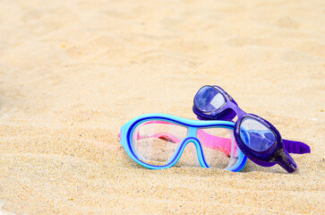 Two pairs of glasses for swimming on a sand background