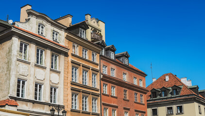 Fototapeta premium Colorful historic buildings against a clear blue sky in Warsaw, capturing the charm of the city in springtime