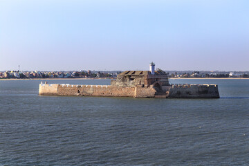 Pani Kotha prison in the distance. Shows the blue water, waves, ocean Walls of diu fort with view of Old Diu City, Portuguese, located in Diu district of Union Territory Daman and Diu India 