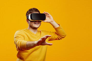 concentrated unshaven man in yellow sweater posing isolated on orange background. Watching in...