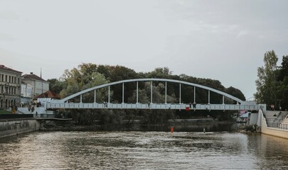 European city with river and bridge, embankment with bars for people on a summer day