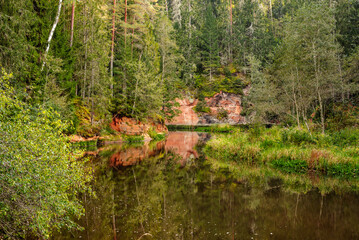 Red sandstone cliffs on Brasla river in Latvia in September