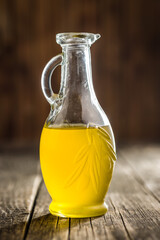 Bottle of organic unfiltered extra virgin olive oil on wooden table.