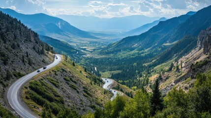 Winding mountain pass with switchbacks and sharp curves leading toward a distant valley with a convoy of cars enjoying the thrilling drive