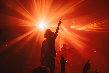 Fototapeta premium Silhouette of a performer on stage under intense red lighting with dramatic pointing gesture