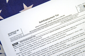 Naklejka premium Self Employment Tax form on the American flag backdrop. 1040 for self-employment tax background