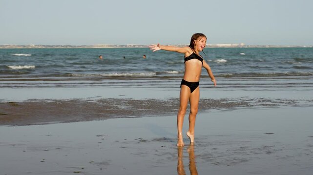Child girl doing gymnastics exercise cartwheel at the beach