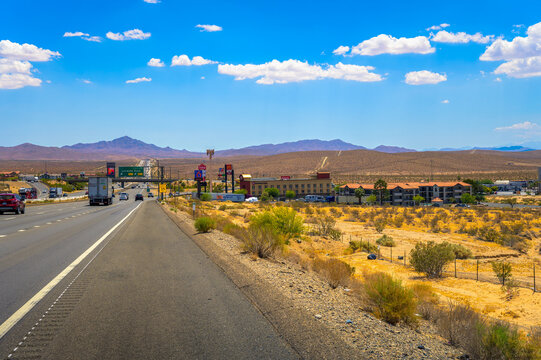Barstow, California, USA - June 17, 2023 : Sunny day on the Mojave Freeway (I-15) through Barstow, California with traffic, commercial signs, and mountainous backdrop.