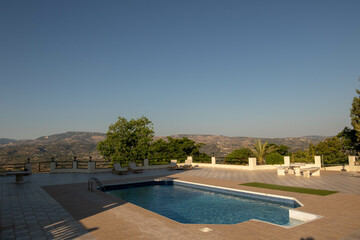 Swimming pool area and sun loungers overlooking Cypriot hills and mountains