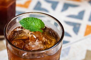 A glass of refreshing iced tea with ice cubes and mint leaves as a garnish