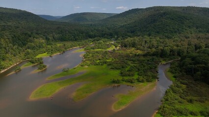 Creek River and Stream flowing through remote forest wilderness with Mountains in summer sunshine while on camping trip for hiking and walking in Nature