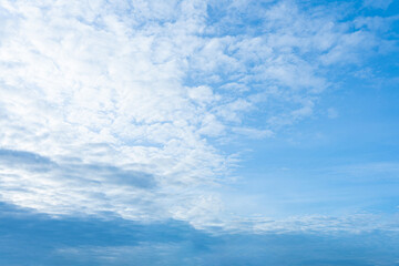 Fluffy white clouds drift across a clear blue sky, painting a beautiful summer day