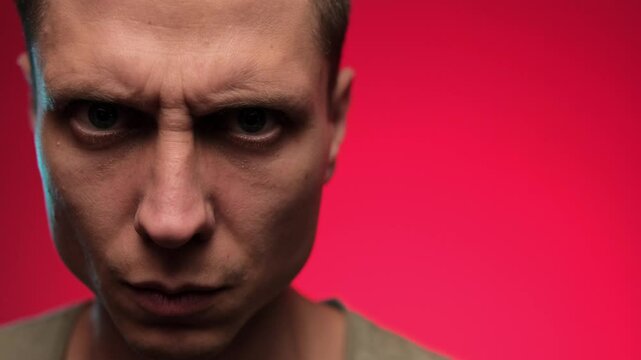 Closeup on man angry facial expression. Red background with space for text.