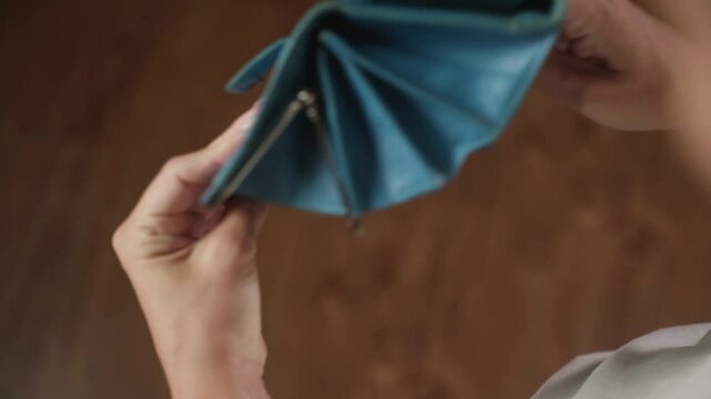Woman shows an empty wallet, revealing a lack of money inside. The scene highlights financial struggles and the challenges of managing personal finances