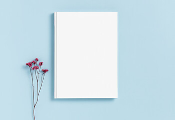 Mockup of a white hardcover book on a blue background dried gypsophila flower. Blank template for your design and advertising in a minimalist style. Flat lay