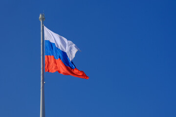 A large flag of the Russian Federation on a blue sky background