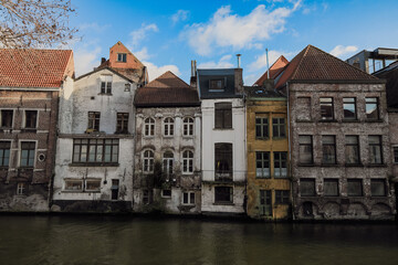 Historic buildings along the waterway in Ghent, Belgium, showcasing architectural diversity under a clear blue sky