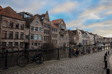Picturesque canal view in Ghent showcasing historic buildings, bicycles, and serene atmosphere during the evening light