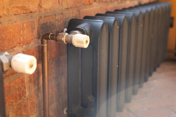 Classic metallic radiator installed in a cozy indoor space with exposed brick wall