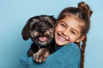 Girl in blue sweater holding happy black dog indoors.