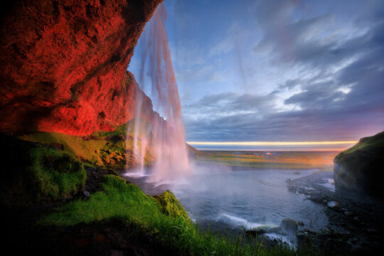 View of seljalandsfoss waterfall cascading down a majestic cliff with lush greenery under a serene sunset, seljalandsfoss, Iceland.