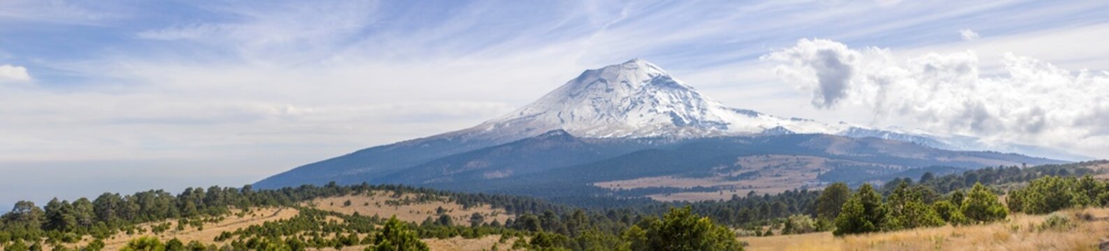 View of majestic snowcapped Popocatepetl volcano with panoramic landscape and serene sky, Amecameca, Mexico.
