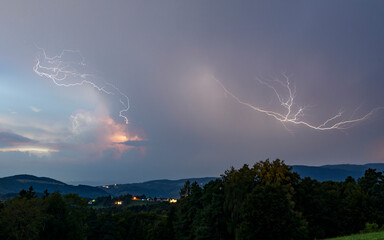 View of dramatic lightning during a thunderstorm over the hills and trees at night, Graz, Styria, Austria.