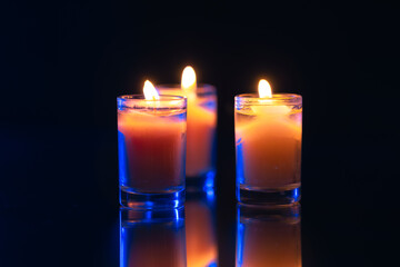 Burning candle on black background with backlight. Memorial Day.