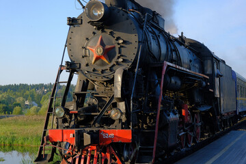 A retro locomotive, an old train with carriages, is moving along the railway.