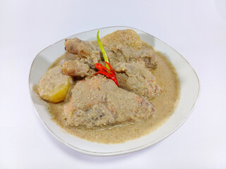 Gulai ayam, an Indonesian dish from Sumatra, with chicken, potatoes, and chili in a savory spiced coconut broth, served in a white bowl against a clean white background