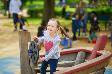 Adorable preschooler girl on playground on a sunny day. Preschooler child playing outdoors. Outdoor activities for kids.