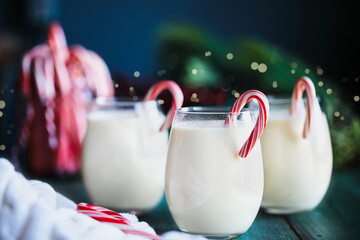 Creamy eggnog with candy canes over green background