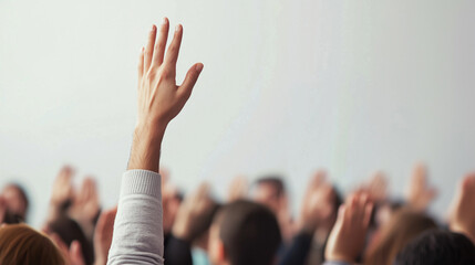 A close-up of a raised hand in a crowd, symbolizing participation, engagement, volunteering, or asking questions in a group setting such as a classroom, meeting, or seminar.